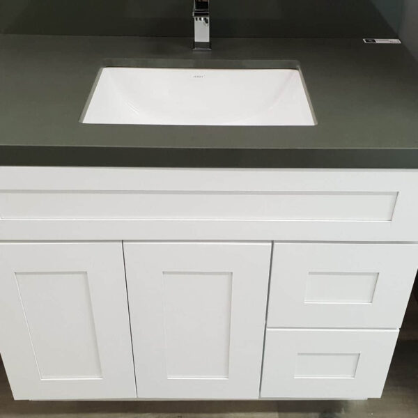 White bathroom vanity with green countertop and modern faucet.