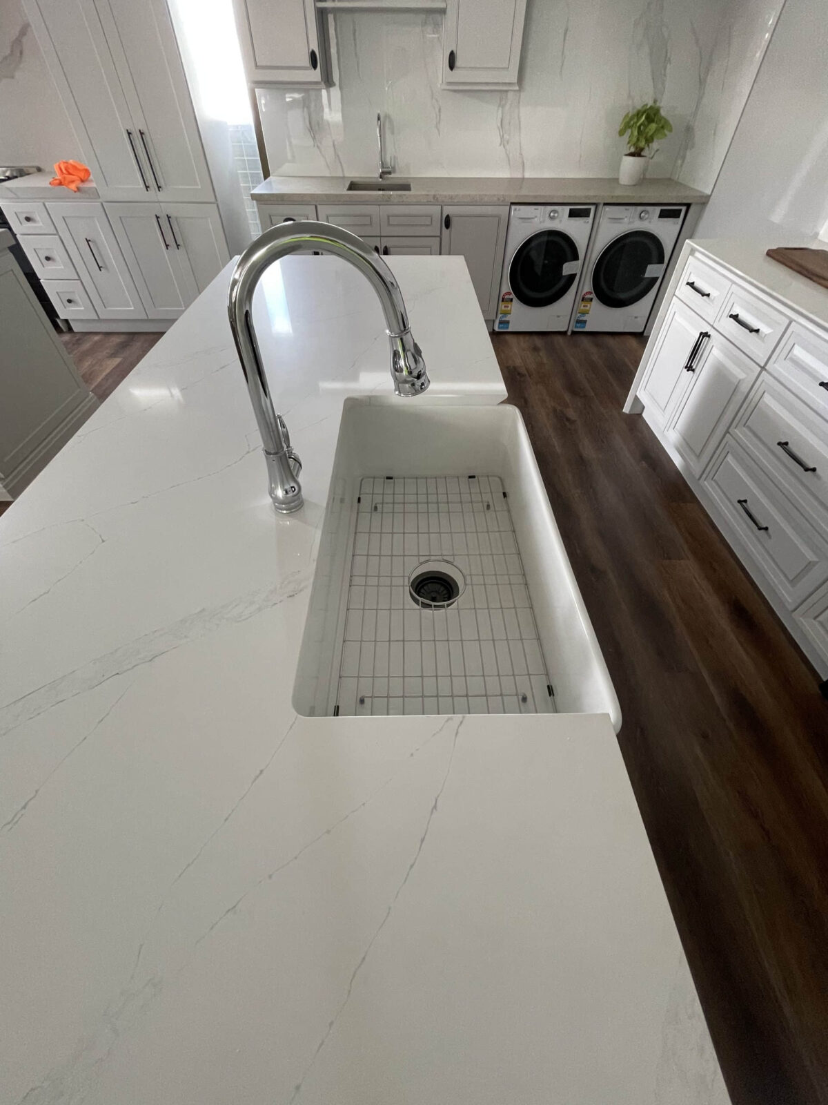 Modern kitchen with marble countertop, sink, and laundry appliances.