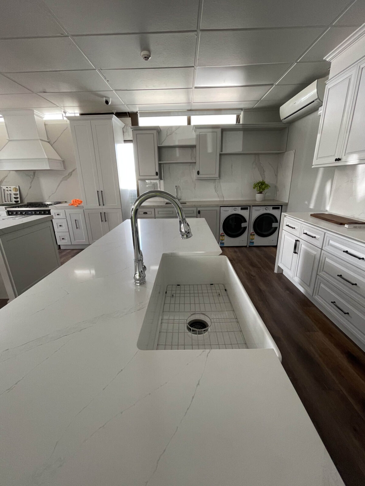 Modern kitchen with white cabinetry, island sink, and laundry appliances.
