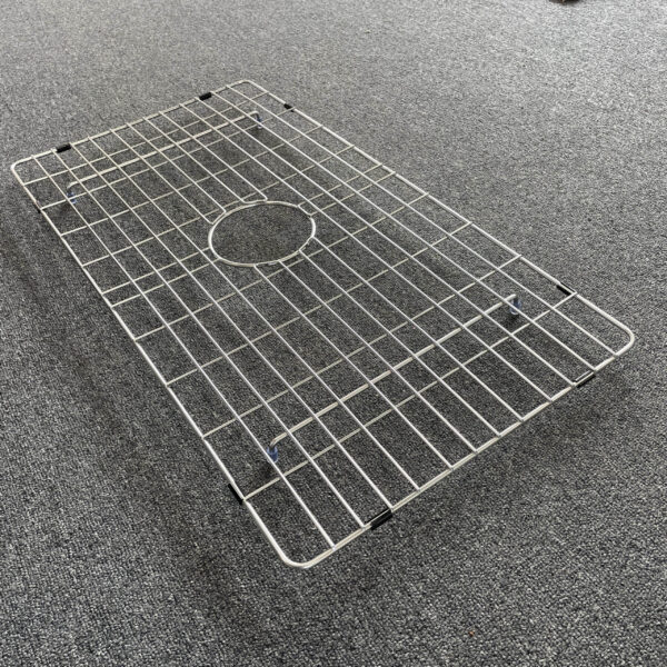 Stainless steel sink grid on gray carpet.