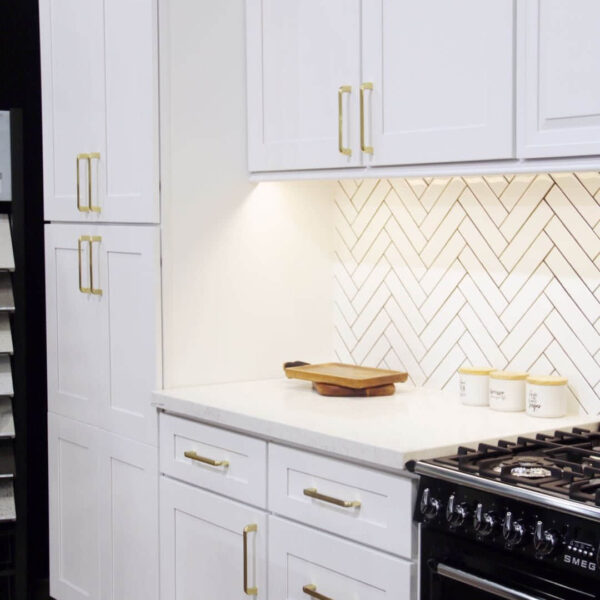 Modern kitchen with white cabinets and herringbone backsplash.
