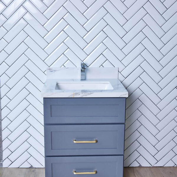 Gray bathroom vanity with herringbone tile backsplash.