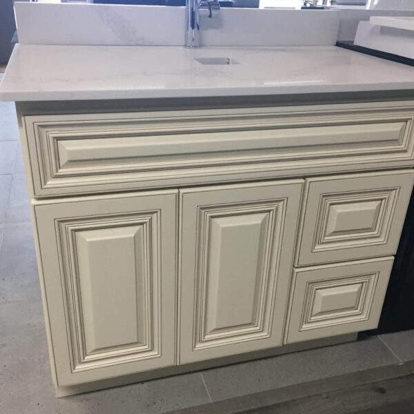 White kitchen cabinet with intricate panel design and marble countertop.