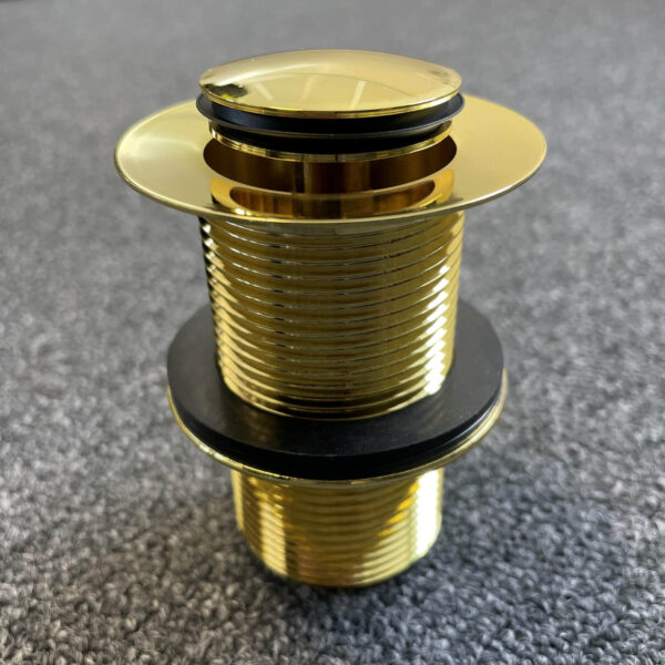 Gold pop-up waste drain on textured surface.