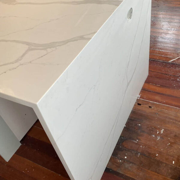 Calacatta Sky Quartz countertop with subtle veining on wooden floor.