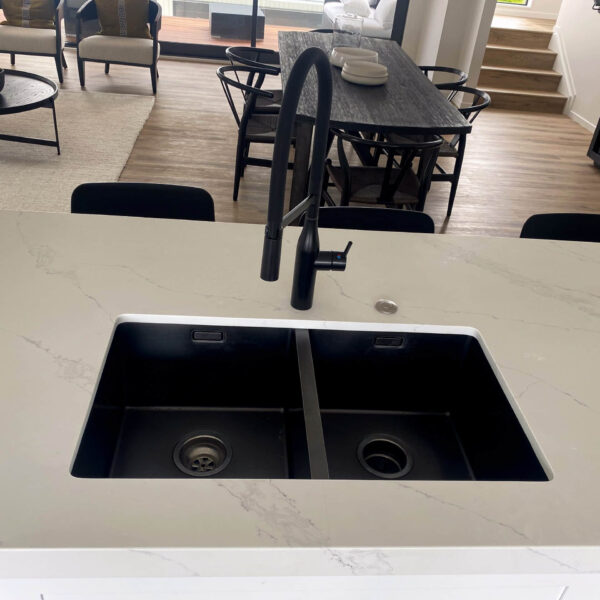 Modern kitchen sink with black faucet and marble countertop.
