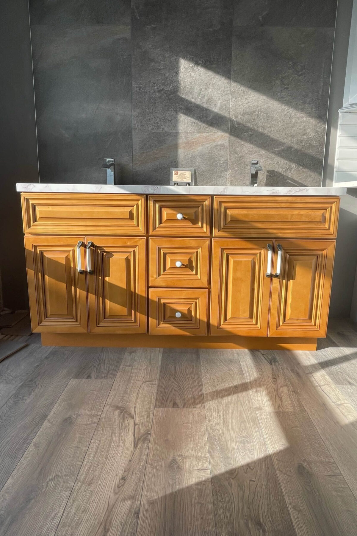 Wooden kitchen cabinet with marble countertop in sunlight.