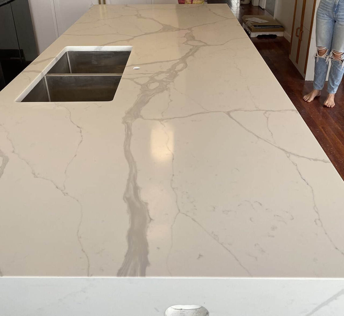 Marble kitchen countertop with sink, person standing nearby.