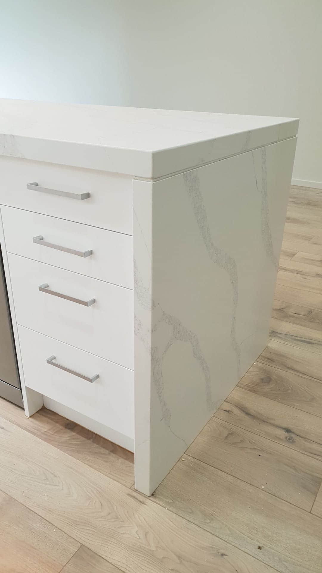 White marble kitchen island with drawers and silver handles.