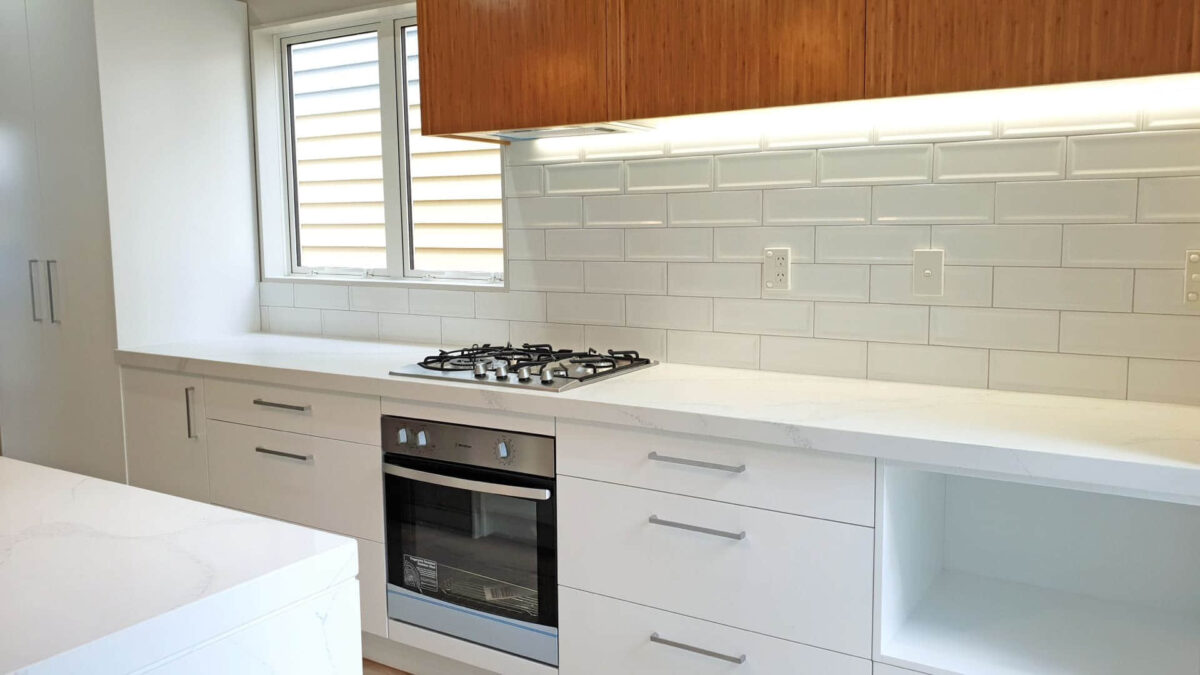 Modern kitchen with white cabinets, marble countertop, and gas stove.